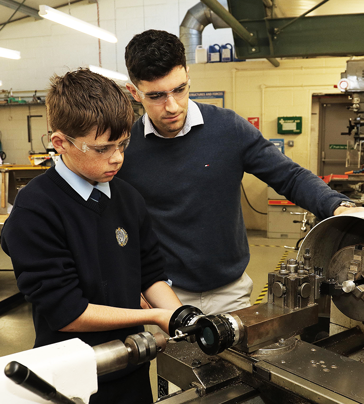 A teacher showing a second level student how to use engineering equipment